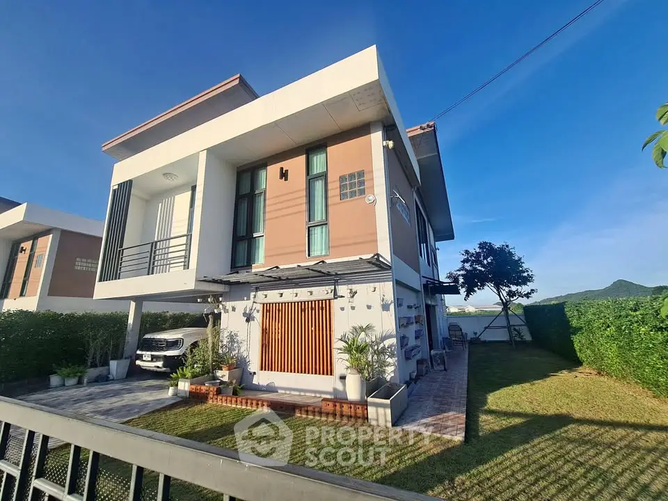 Modern two-story house with landscaped garden and driveway in sunny setting