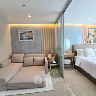 Modern living room with cozy sofa and elegant bedroom separated by glass partition in luxury apartment.