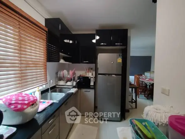 Modern kitchen with sleek cabinets and stainless steel fridge in a cozy apartment.