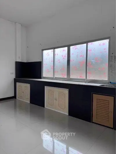 Spacious kitchen with large window and ample storage cabinets