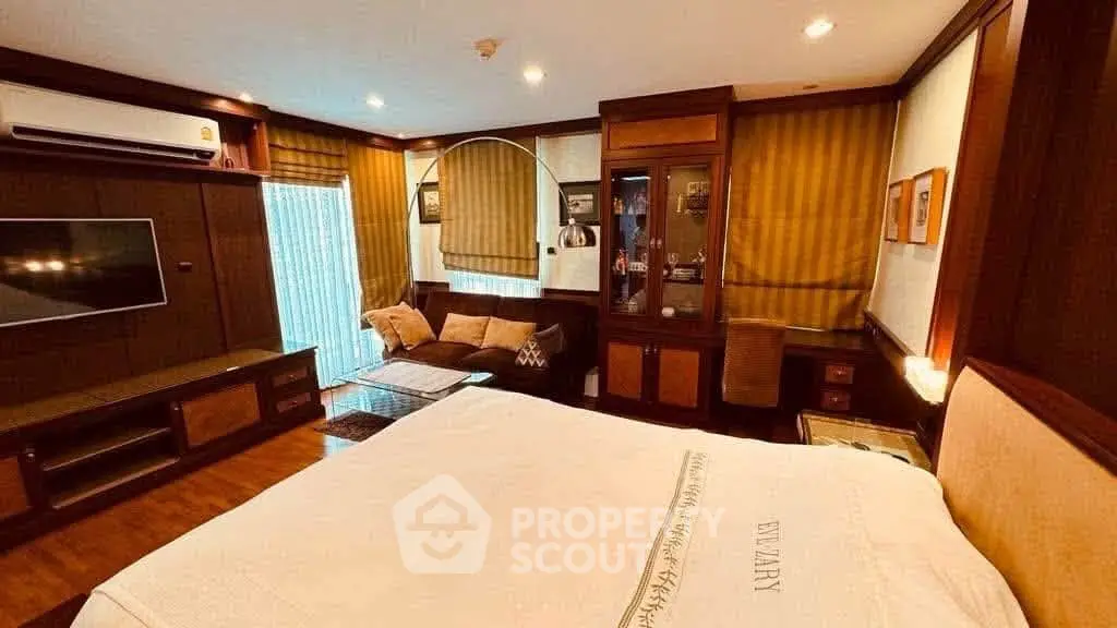 Luxurious bedroom with elegant wooden furnishings and cozy seating area, perfect for relaxation and comfort.