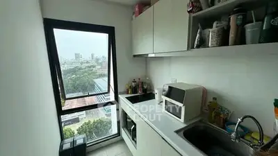 Modern kitchen with city view, sleek cabinetry, and built-in appliances in a high-rise apartment.