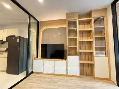 Modern living room with sleek built-in shelving and TV unit, adjacent to a stylish kitchen area.