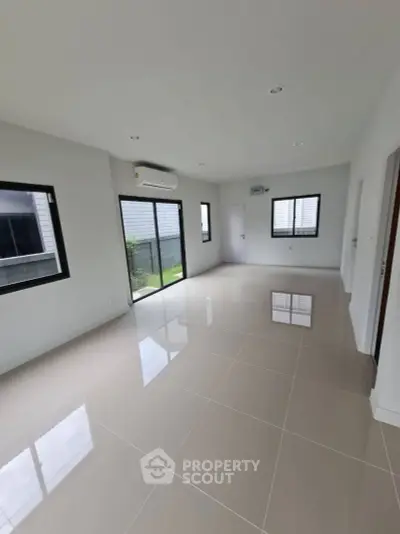Spacious modern living room with large windows and glossy tiled floors