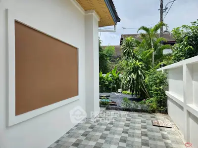 Charming outdoor garden area with lush greenery and tiled patio, perfect for relaxation and entertaining.