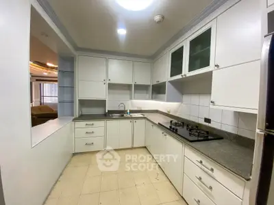 Spacious kitchen with modern gas stove and ample cabinetry in a well-lit apartment.