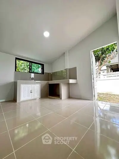Spacious kitchen with open layout and natural light, featuring modern cabinetry and tiled flooring.