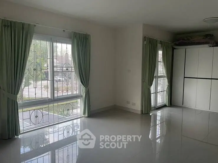 Spacious unfurnished room with large windows and green curtains, perfect for customization.