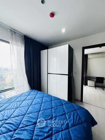 Modern bedroom with blue bedding and city view from large window