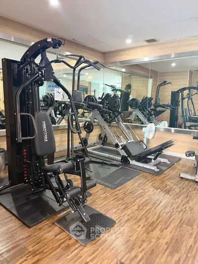 Modern gym with state-of-the-art fitness equipment and mirrored walls in a residential building.