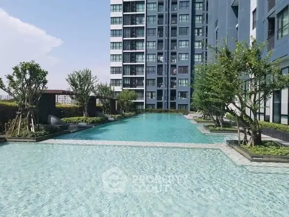 Luxurious residential building with a stunning outdoor pool and lush greenery.
