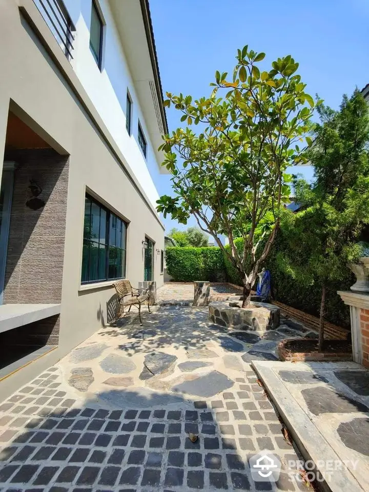 Charming modern home exterior with spacious stone patio and lush greenery