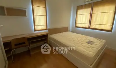Cozy bedroom with natural light, featuring a comfortable bed and wooden furniture, ideal for restful living.