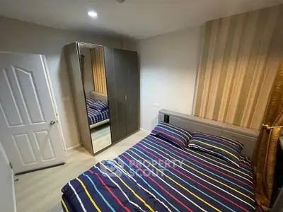 Cozy bedroom with modern striped bedding and mirrored wardrobe in stylish apartment.