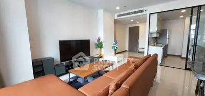 Modern living room with brown leather sofa and sleek kitchen area