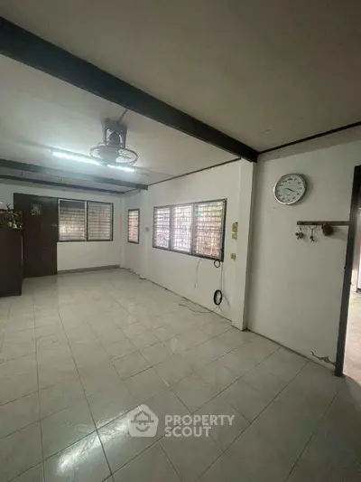 Spacious living room with tiled floor and large windows for natural light.