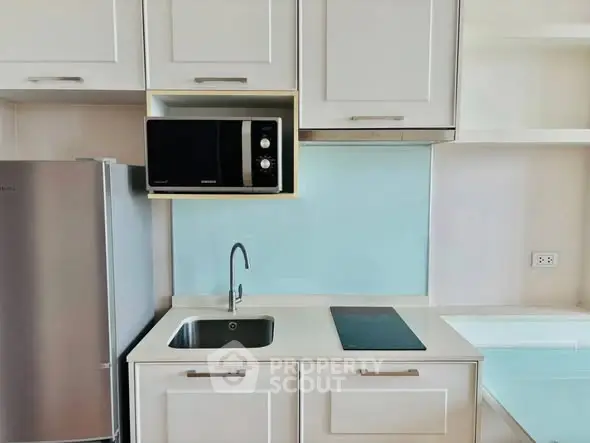 Modern kitchen with sleek cabinetry, built-in microwave, and induction cooktop.