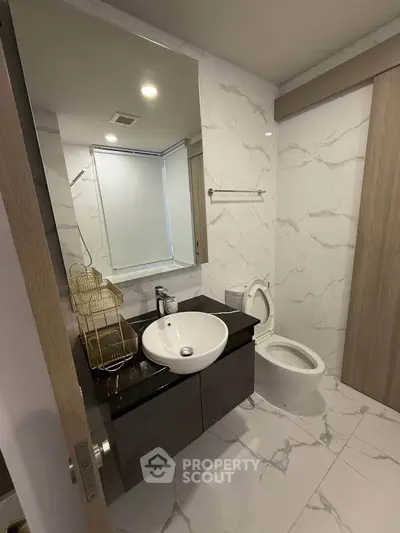Modern bathroom with sleek fixtures and marble tiles, featuring a stylish vanity and contemporary design.