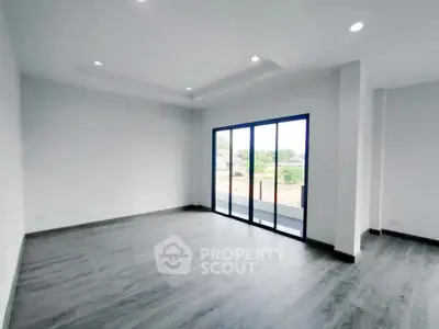 Spacious modern living room with large windows and balcony access.