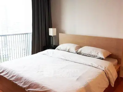 Spacious bedroom with modern decor and large window offering city views.