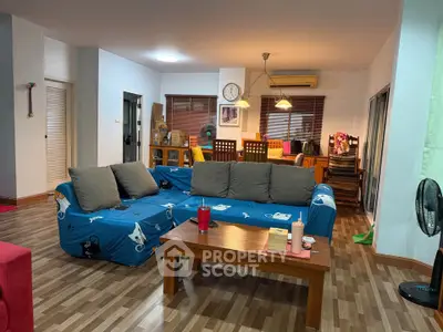 Spacious living room with cozy sofa and wooden flooring, perfect for relaxation and entertaining.