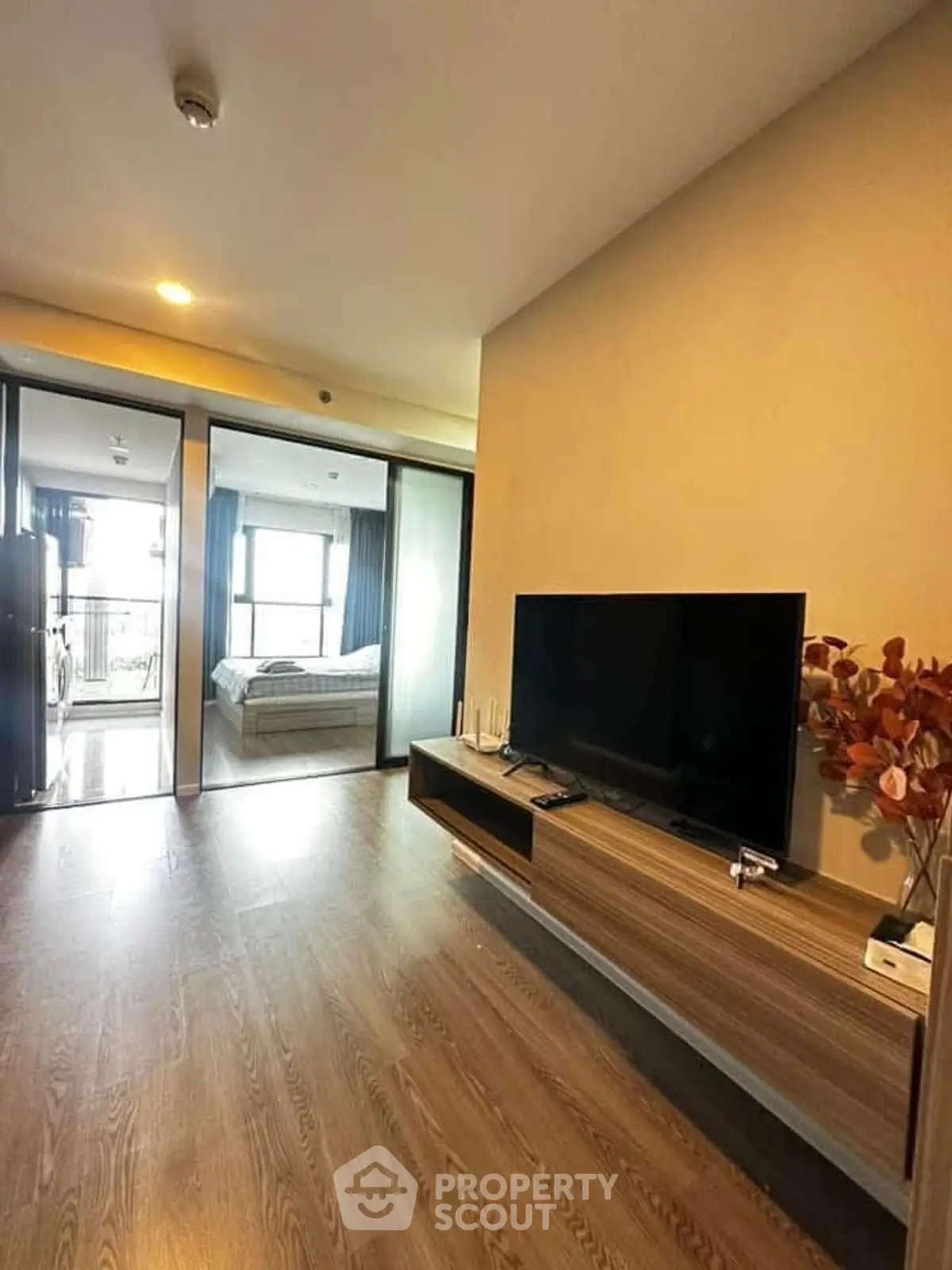 Modern living room with sleek TV unit and view into a cozy bedroom