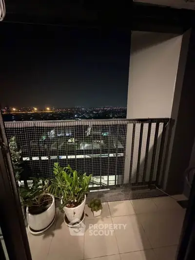 Stunning night view from a high-rise balcony with city lights and potted plants.