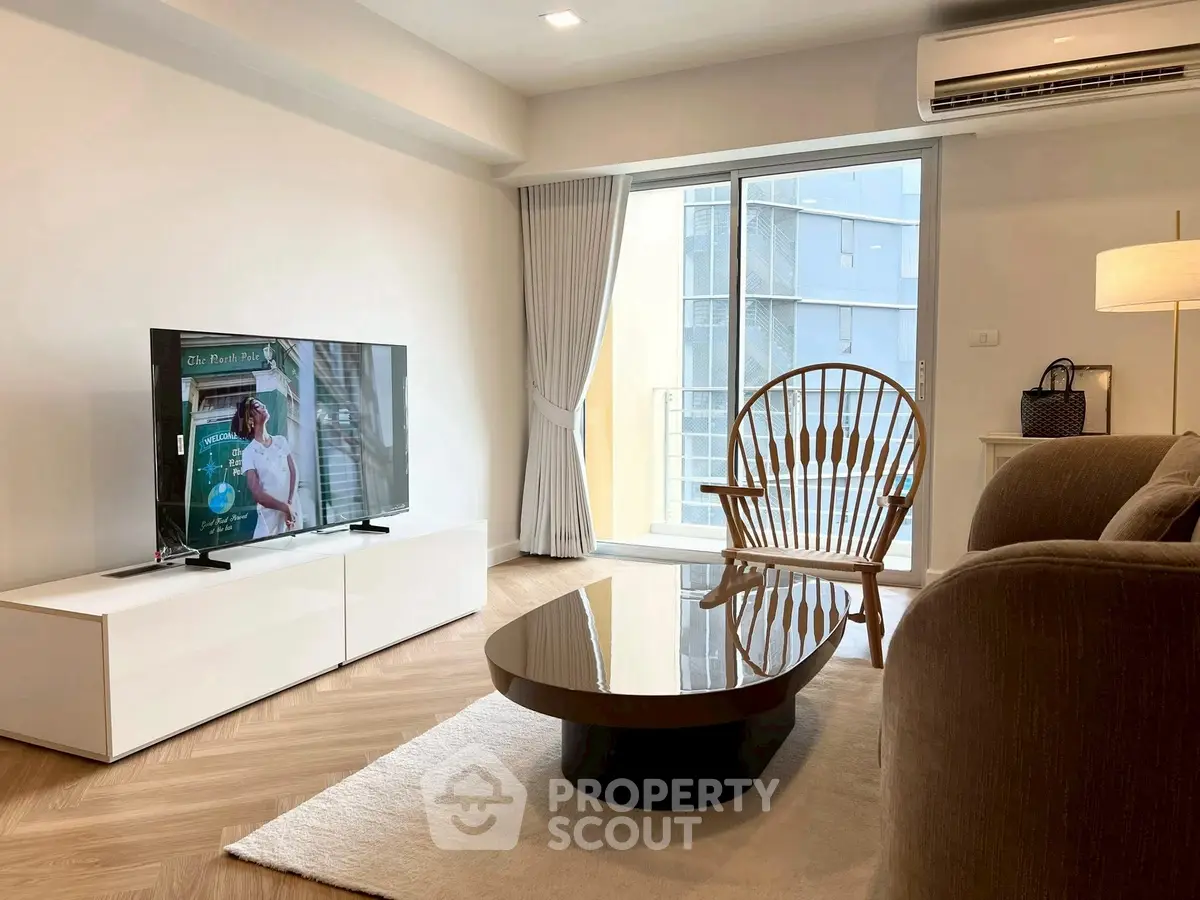 Modern living room with stylish furniture and large window offering natural light.