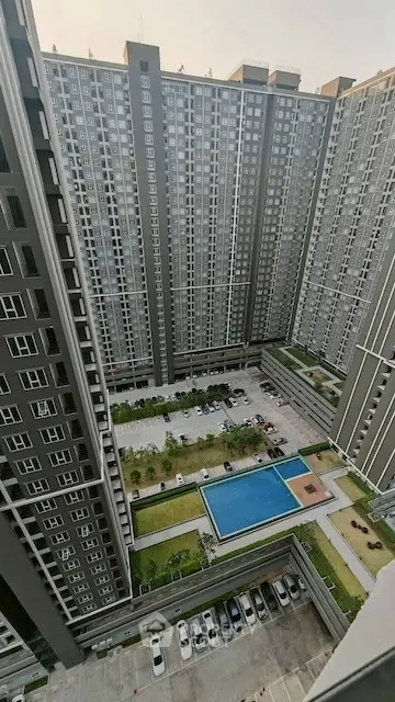 High-rise residential complex with pool and garden view from upper floor.
