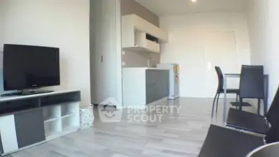 Modern open-plan living room with sleek kitchen and dining area, featuring contemporary furniture and minimalist design.