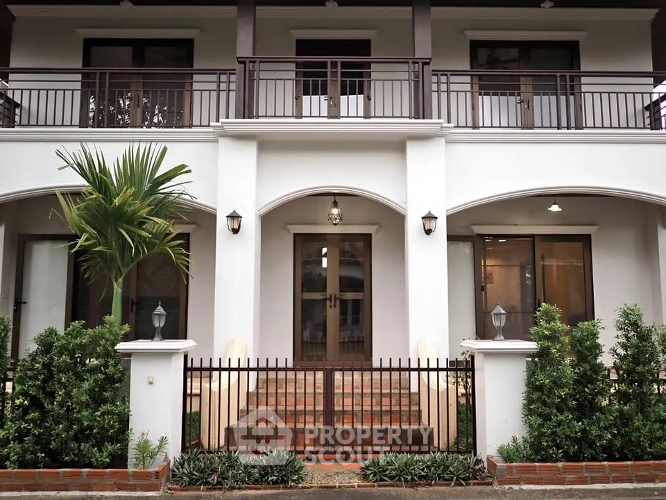 Elegant two-story home with lush greenery and gated entrance