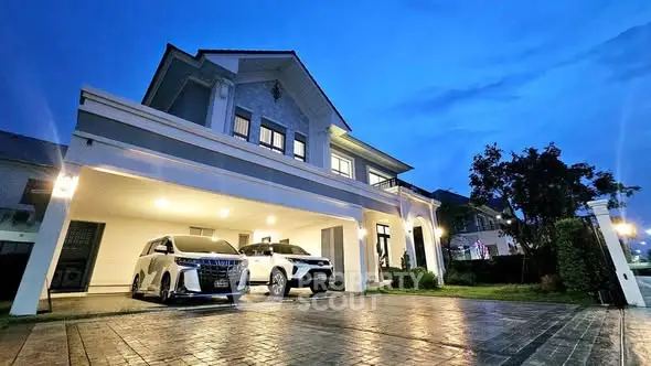 Luxurious modern house with spacious driveway and two cars parked at dusk.