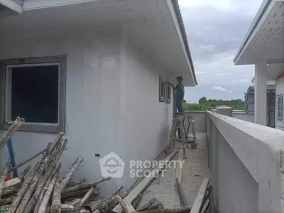 Exterior view of a building under construction with scaffolding and worker