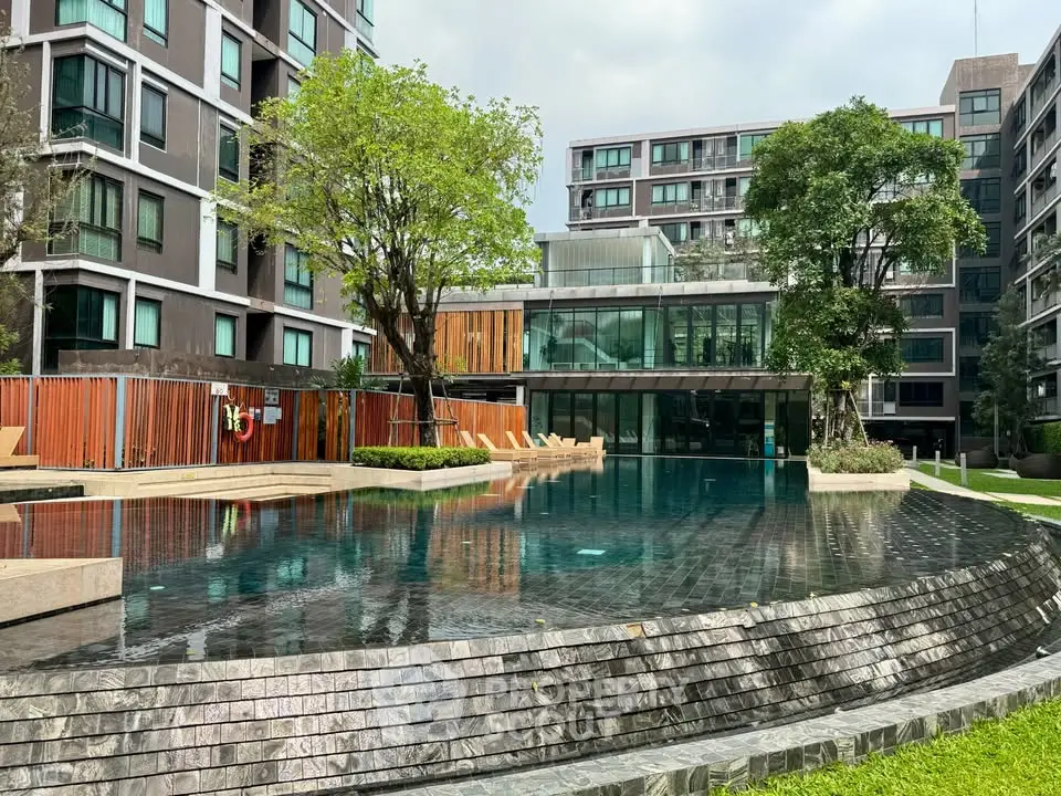 Luxurious modern apartment complex with stunning pool and lush greenery.