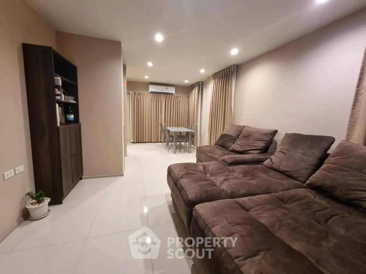 Spacious living room with plush brown sectional sofa and modern dining area.