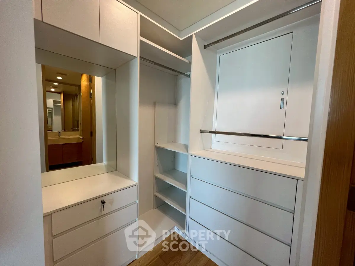 Spacious walk-in closet with modern white cabinetry and ample storage space.