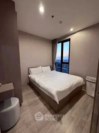 Cozy bedroom with modern decor and large window offering city view