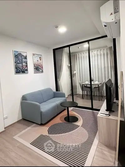 Modern living room with stylish decor and glass partitioned dining area.