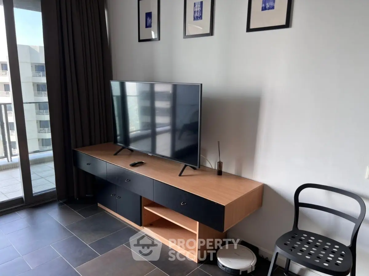 Modern living room with sleek TV setup and balcony view, perfect for urban living.