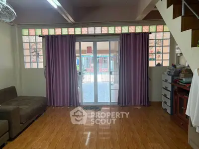 Spacious living room with wooden flooring and large glass doors leading to a patio.