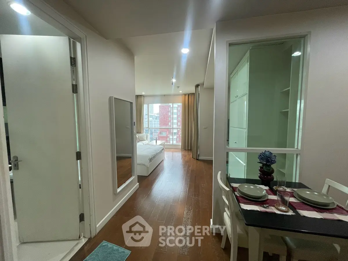 Modern apartment interior with open layout, featuring a cozy dining area and a bright living space with city views.