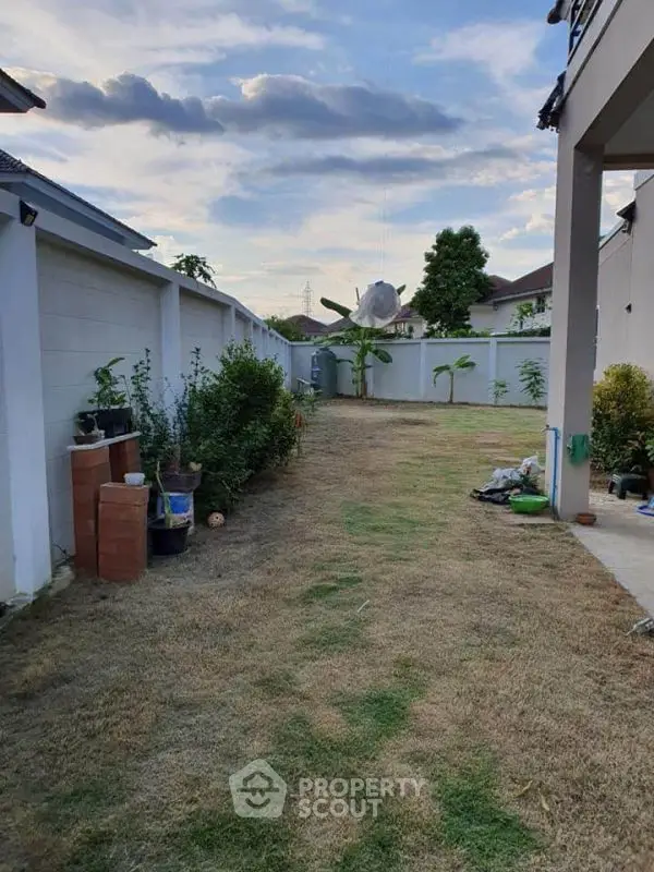 Spacious backyard with lush greenery and clear sky, perfect for outdoor activities and relaxation.