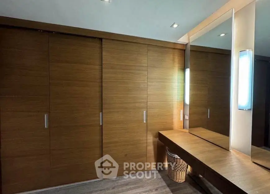 Spacious modern dressing room with wooden sliding doors and large mirror.