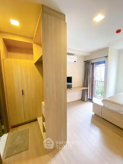 Modern bedroom with wooden flooring, built-in wardrobe, and balcony access in a stylish apartment.