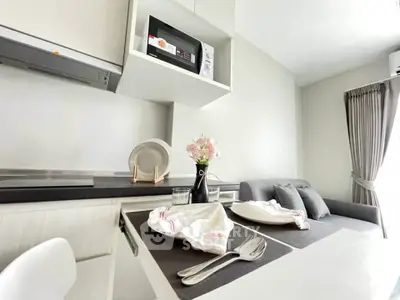 Modern kitchen with dining area and cozy living space in open layout apartment.