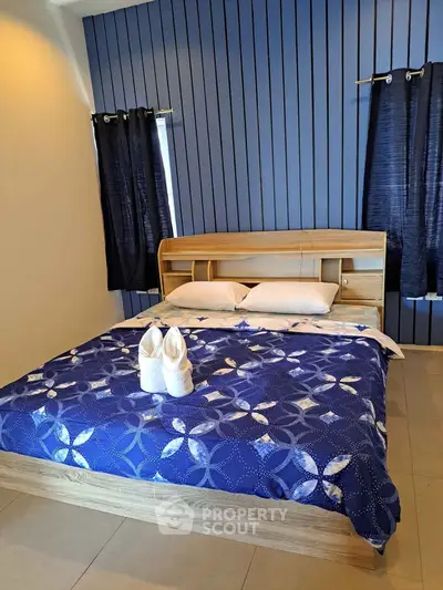 Modern bedroom with stylish blue accent wall and cozy wooden bed frame.