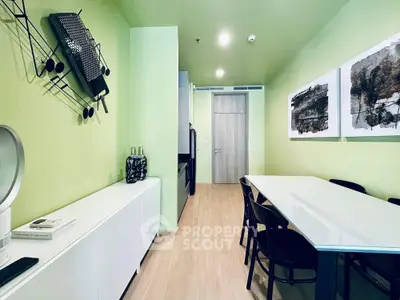 Modern dining area with sleek furniture and abstract art on green walls, perfect for stylish living.