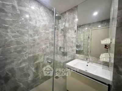 Modern bathroom with glass shower and sleek vanity in luxury apartment