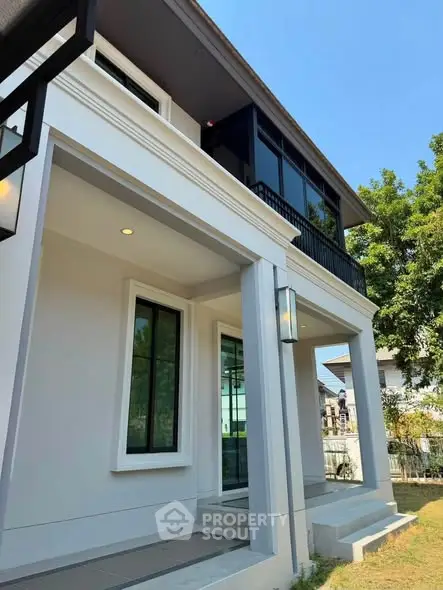 Modern two-story house with sleek design and large windows, surrounded by greenery.