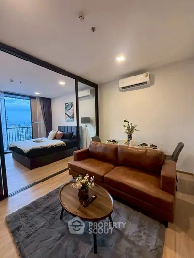 Modern living room with brown leather sofa and view into stylish bedroom